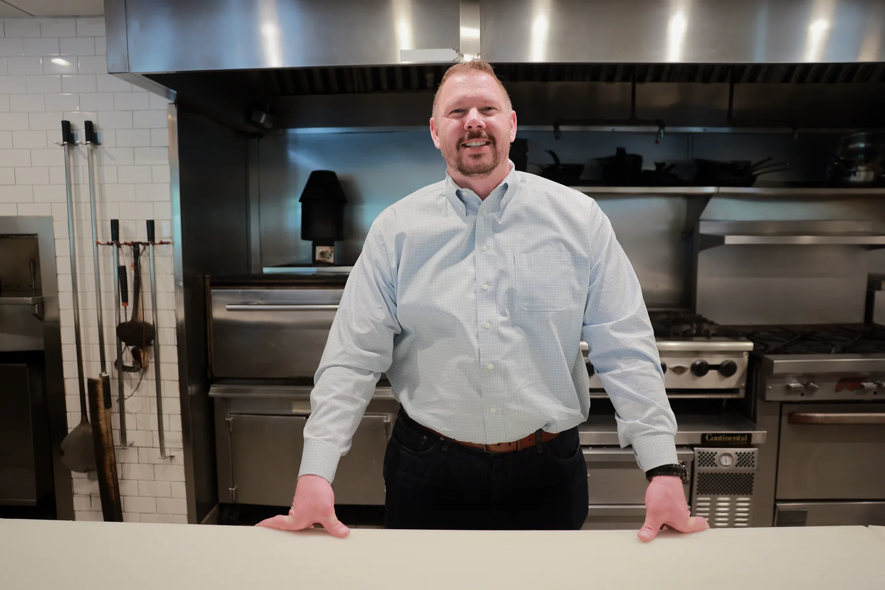 Restaurant operator standing in a kitchen during a planning conversation.