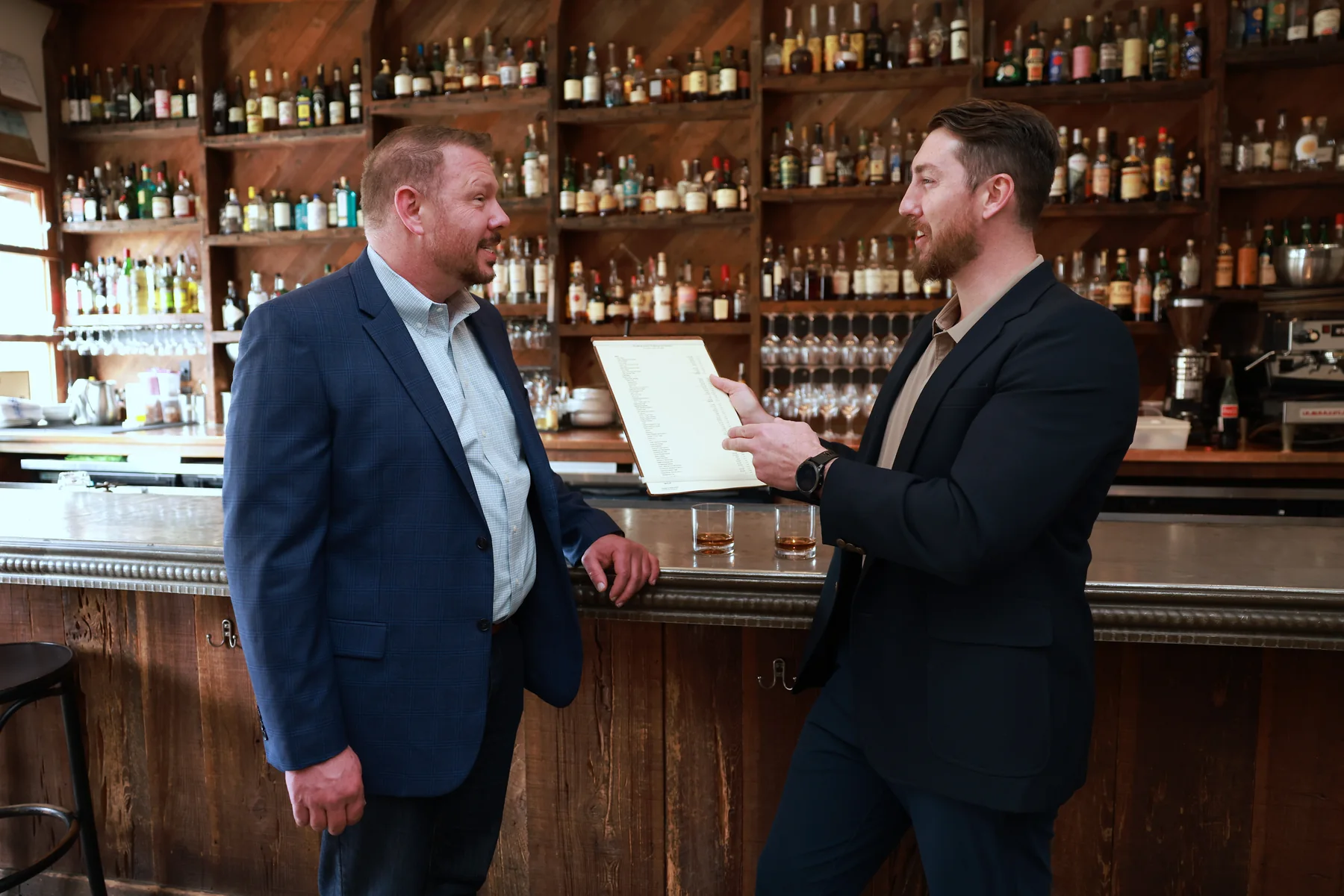Two restaurant advisors discussing a printed report at the bar.